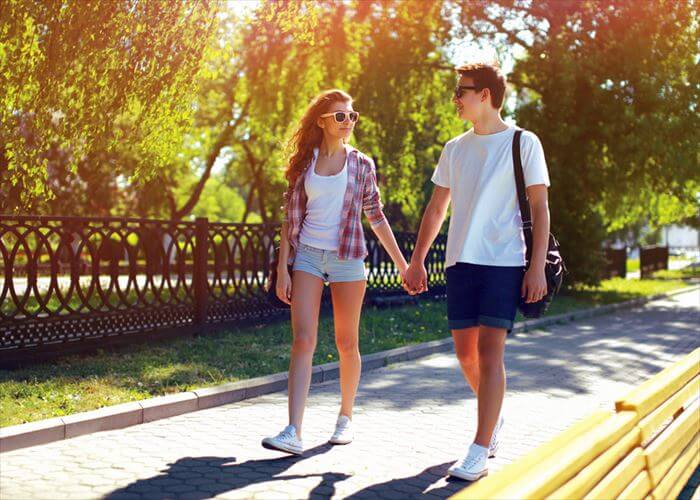 Summer, vacation, fun, relationships and people concept - pretty modern young couple in love walking in sunny summer day