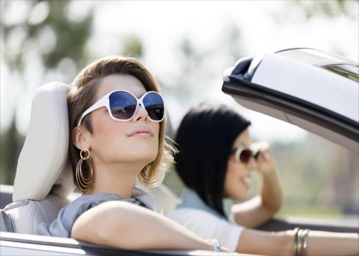 Close up of girls wearing sunglasses in the white car. Little holiday trip of friends