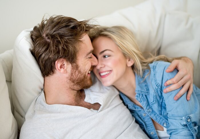 Loving couple relaxing at home lying on the sofa - relationship concepts
