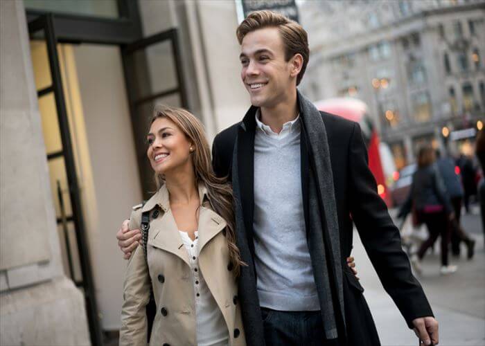 Young couple walking on the street in the city hugging and looking very happy