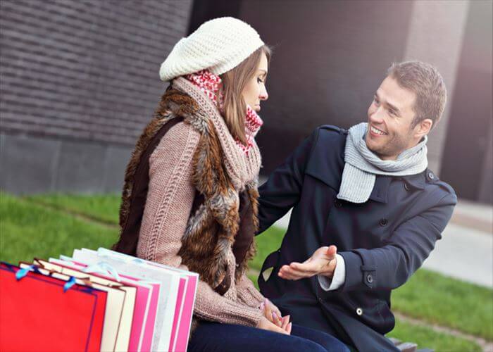 Picture of young man showing disapproval to woman with many shopping bags